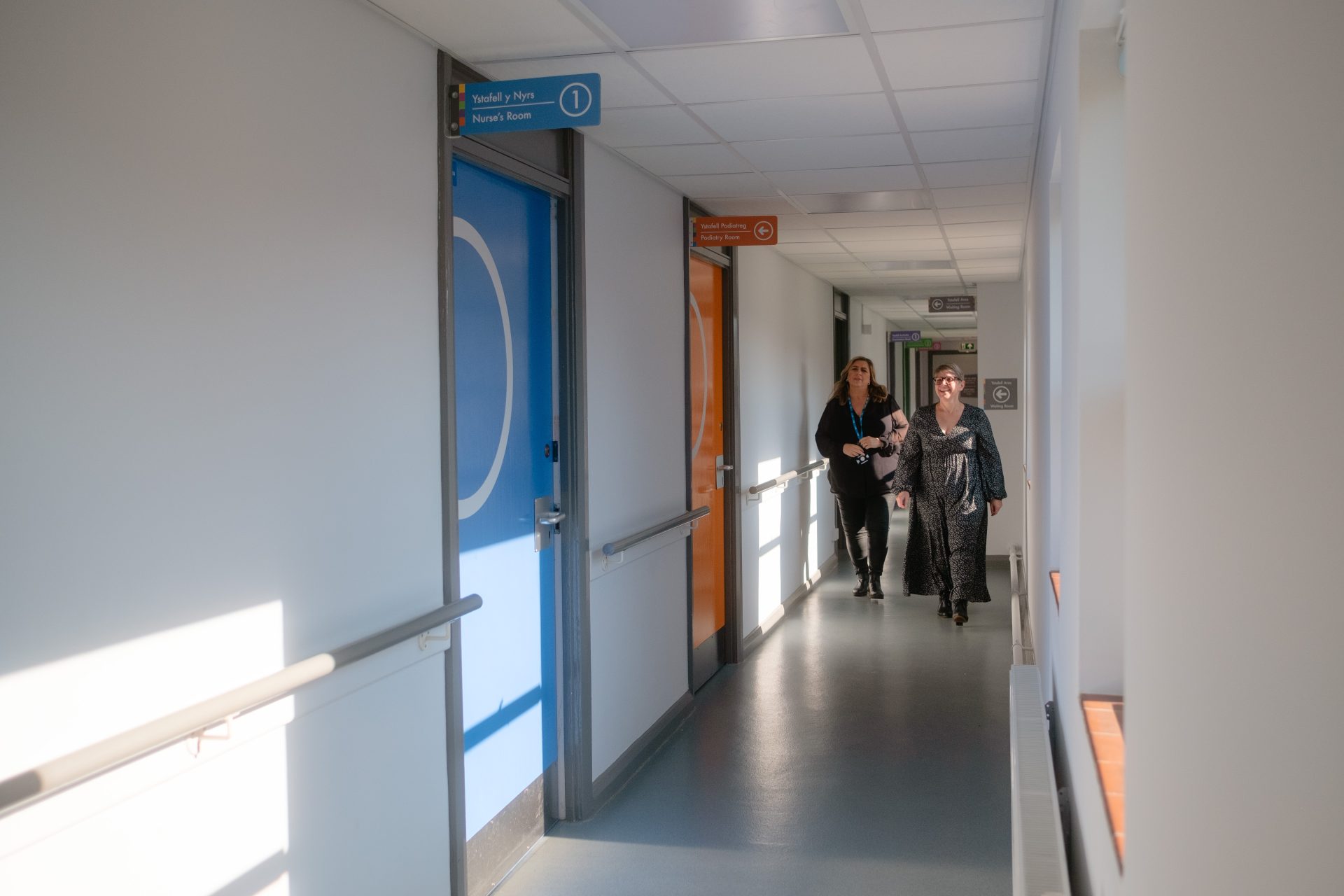 Delwedd o ddau aelod o staff yn y ward gyda signes sy'n ffrindiau i'r gymuned ddementia