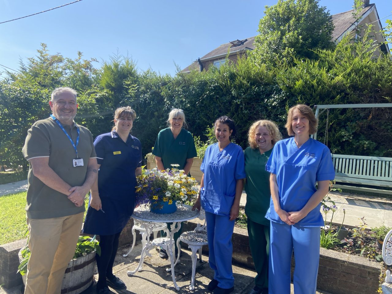 Delwedd o Aelod Tîm Elusen Powys yn Gardd Llanidloes gyda chynrychiolwyr o'r Staff