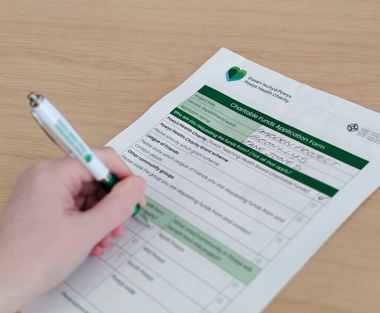 Delwedd agos o rywun yn llenwi ffurflen gais