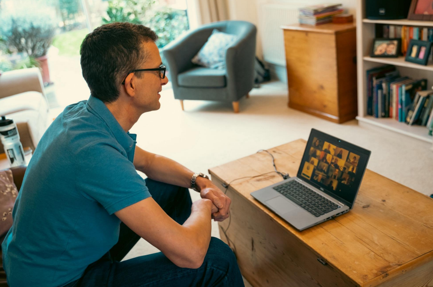 Delwedd o ddyn ar ei danhau gartref yn ymuno â Chyfarfod Teams