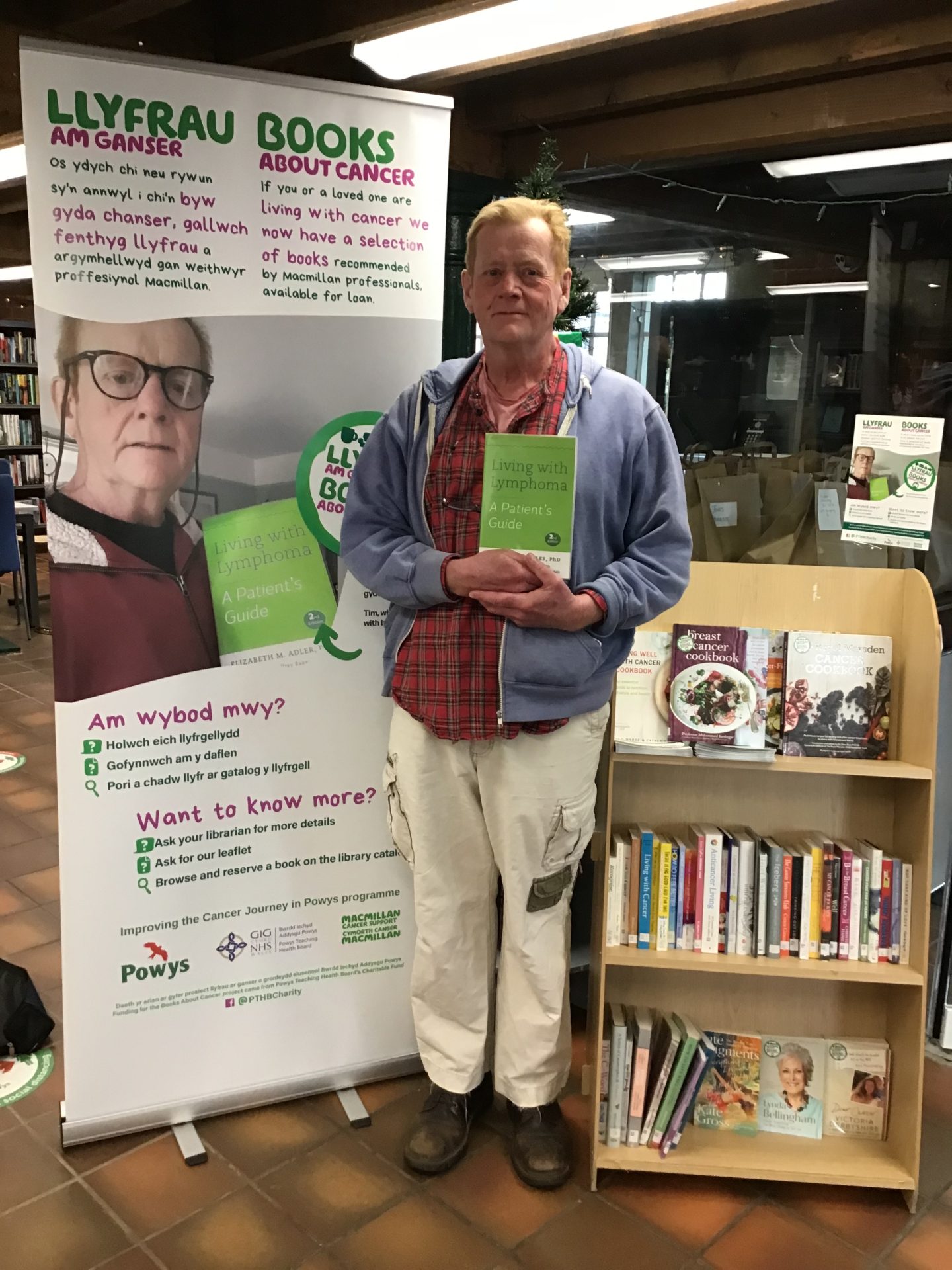 Delwedd yn Gwella Taith Canser a Dyn (Tim) yn dal llyfr