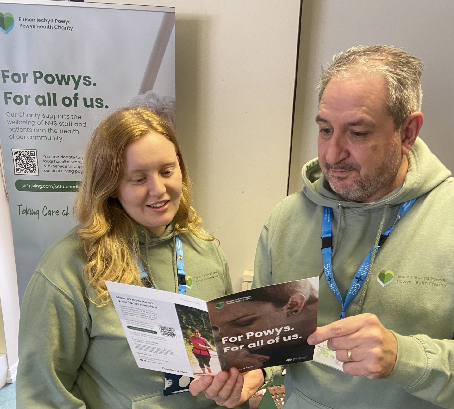 Delwedd o Martin a Shania yn edrych ar daflen gwybodaeth elusen Iechyd Powys.